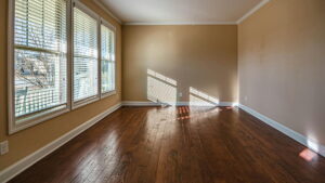 Elegant wooden flooring in Bangalore showcased in a sunlit modern room with large windows and polished hardwood floors