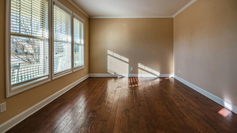 Elegant wooden flooring in Bangalore showcased in a sunlit modern room with large windows and polished hardwood floors